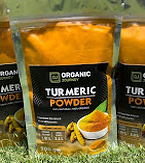 Packed organic turmeric powder pouches standing on grass